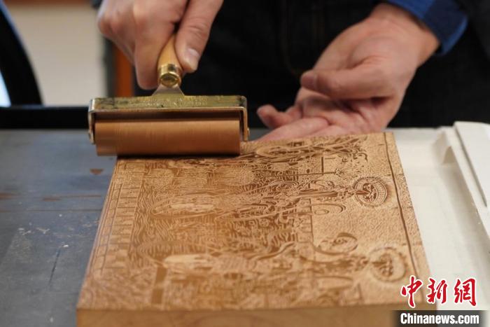 圖為徐晉林工作室工作人員正在給雕好壁畫的版面滾油墨?！【琶赖┰?　攝