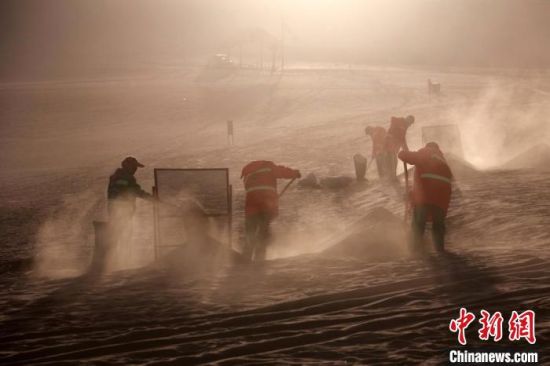 圖為敦煌市鳴沙山月牙泉景區(qū)“駱駝保姆”清理駱駝糞便?！垥粤?攝